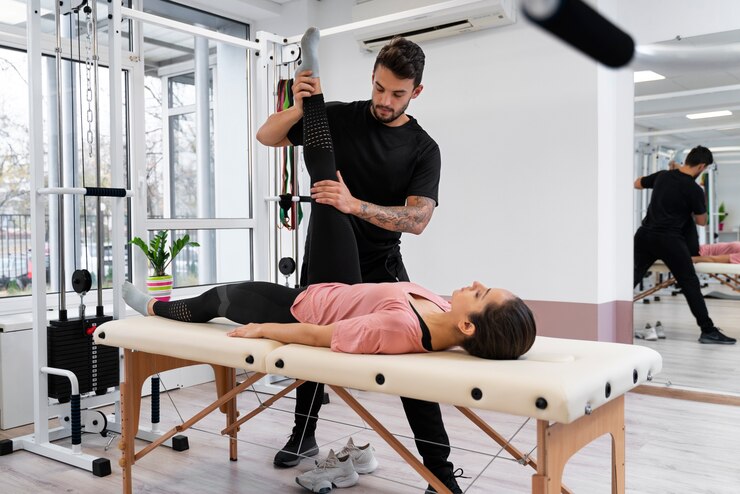 licensed physical therapist assisting client with gym equipment